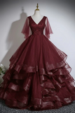 Burgundy ball gown on a mannequin against a plain background