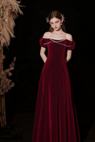 Woman wearing a burgundy off-shoulder dress with pearl details against a dark background