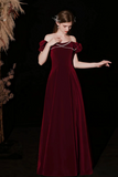 Woman wearing a burgundy velvet dress against a dark background