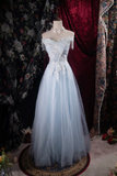 Light blue evening gown on a mannequin against a floral and dark curtain background