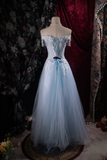 Light blue evening gown on a mannequin against a floral and dark curtain background