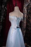 Light blue evening gown on a mannequin against a floral and red curtain background