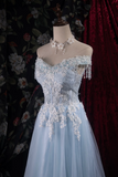 Light blue evening gown with floral embellishments on a mannequin against a dark floral backdrop.
