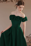 Woman wearing a green off-shoulder dress with a plain background