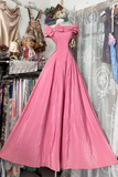 Pink evening gown on a mannequin against a backdrop of clothing racks.