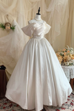 White wedding dress on a mannequin with a floral arrangement in the background