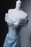 Light blue evening gown with floral embellishments on a mannequin against a dark background