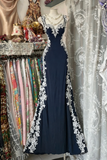 Navy blue evening gown with white lace details on a mannequin in a store setting.