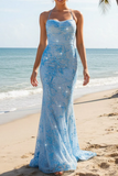 Woman in a blue lace evening gown on a beach