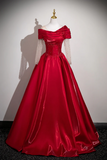 Red evening gown on a mannequin against a plain background
