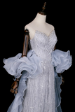 Elegant silver evening gown on a mannequin against a black background