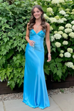 Woman in a blue evening gown standing in front of greenery