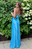 Woman in a blue evening gown standing in front of greenery and flowers
