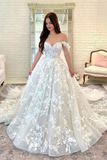 Woman wearing a white lace wedding dress in a room with a mirror and sofa.