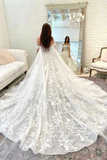Woman in a white wedding dress with floral details standing in a room.