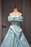 Light blue off-shoulder gown with embellishments on a mannequin against a gray background