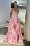 Woman wearing a pink evening gown in a room with a table and flowers.