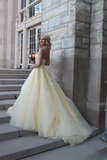 Woman in a yellow dress standing on steps outside a stone building