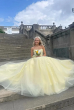 Woman in a yellow dress standing on steps with a scenic background