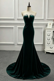 A strapless emerald green velvet mermaid gown with a sweetheart neckline and silver rhinestone trim, displayed on a mannequin in a room with white paneled walls.