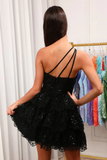 A woman shown from the back wearing a short black lace dress with thin crisscross strappy back details and sequined layers. She is standing in a fitting room with a rack of colorful dresses in the background.