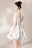 A woman modeling a short white satin dress from the back, showing a scoop neckline, lace-up back, and flared skirt, set against a soft beige studio background.
