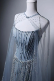 A light blue tulle evening gown with intricate silver beadwork and sequins, displayed on a white mannequin against a dark gray background.