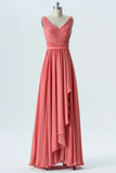 A sleeveless coral pink formal gown displayed on a mannequin against a light gray studio background. The dress features a draped, ruched bodice with a V-neckline and a flowing, tiered skirt with an asymmetrical ruffle hem.
