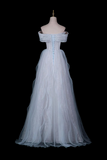 A long off-the-shoulder tulle dress in a very pale icy blue or white, displayed on a mannequin against a solid black background. The dress features a structured corset-style bodice with lace-up detailing down the center back and a voluminous layered tulle skirt.