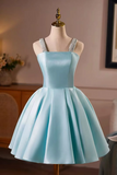 A light blue short formal dress with a pleated skirt and lace straps, displayed on a mannequin in an indoor room setting.