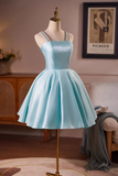 A light blue satin short dress with silver embellished straps, displayed on a mannequin in a styled indoor room setting.