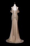 A floor-length champagne beige evening gown with intricate beadwork and sequins, displayed on a white mannequin against a solid black background.