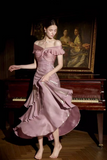 A woman wearing a dusty mauve off-the-shoulder midi dress with ruffled layers and a bow detail, posing in front of a dark grand piano and a classical painting.