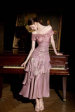 A woman in a shimmering dusty pink off-the-shoulder midi dress with layered ruffles, posing next to a dark wooden grand piano in a dimly lit room with a painting in the background.