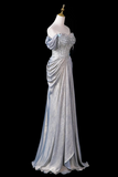 A floor-length off-the-shoulder evening gown in shimmering silver with a beaded embellished bodice, displayed on a white mannequin against a solid black background.