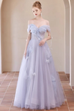 A woman models an off-the-shoulder light lavender tulle ball gown with layered ruffles and floral appliqués in a warm-toned arched hallway.
