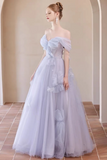 A woman models an off-the-shoulder lavender tulle ball gown with a fitted bodice and voluminous layered skirt in a warm-toned arched hallway.