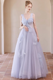 A woman modeling a sleeveless light lavender formal gown with a sweetheart neckline, ruffled bodice, and voluminous tulle skirt in an indoor architectural setting with beige walls and tiled floor.