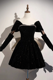 A black velvet short dress with puff sleeves and a sparkling beaded neckline, displayed on a mannequin against a white background.