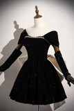 A black velvet off-the-shoulder dress with sparkling sequins and a jeweled neckline, displayed on a mannequin with long black gloves against a white background.