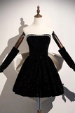 A black strapless velvet dress with a sweetheart neckline, embellished with rhinestones across the bust and a flared skirt, displayed on a mannequin with long black gloves.