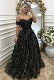 A woman takes a mirror selfie wearing a formal off-the-shoulder black lace and tulle ball gown with a full skirt, standing in an elegant room with a large gold mirror and white flowers.